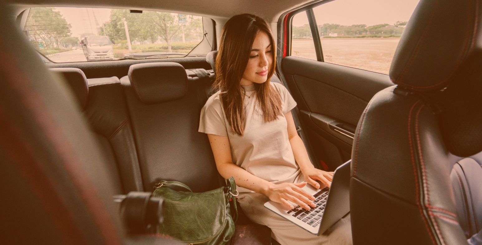 kobieta na tylnym siedzeniu w samochodzie pracująca na laptopie