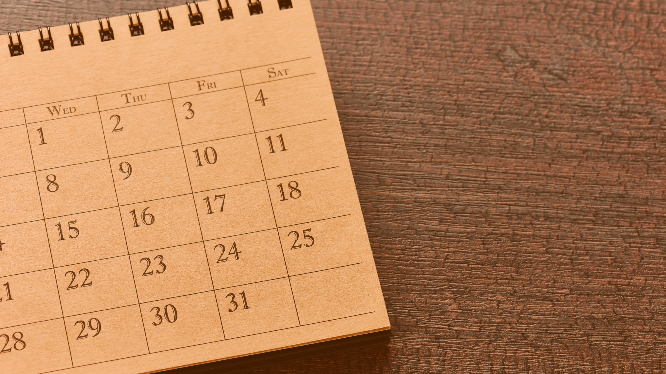 Kalendarz miesięczny leżący na biurku. 