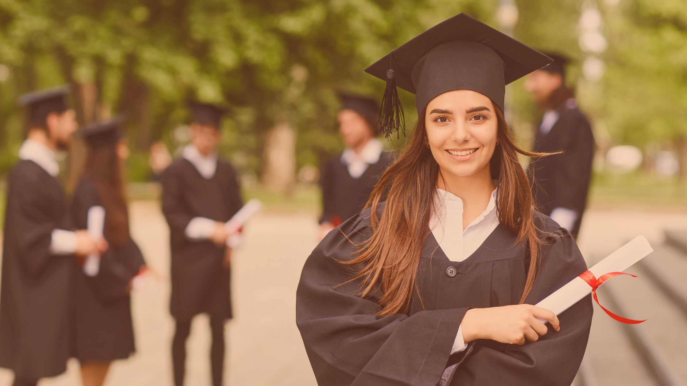 Absolwentka ubrana w togę, w ręce trzyma dyplom.