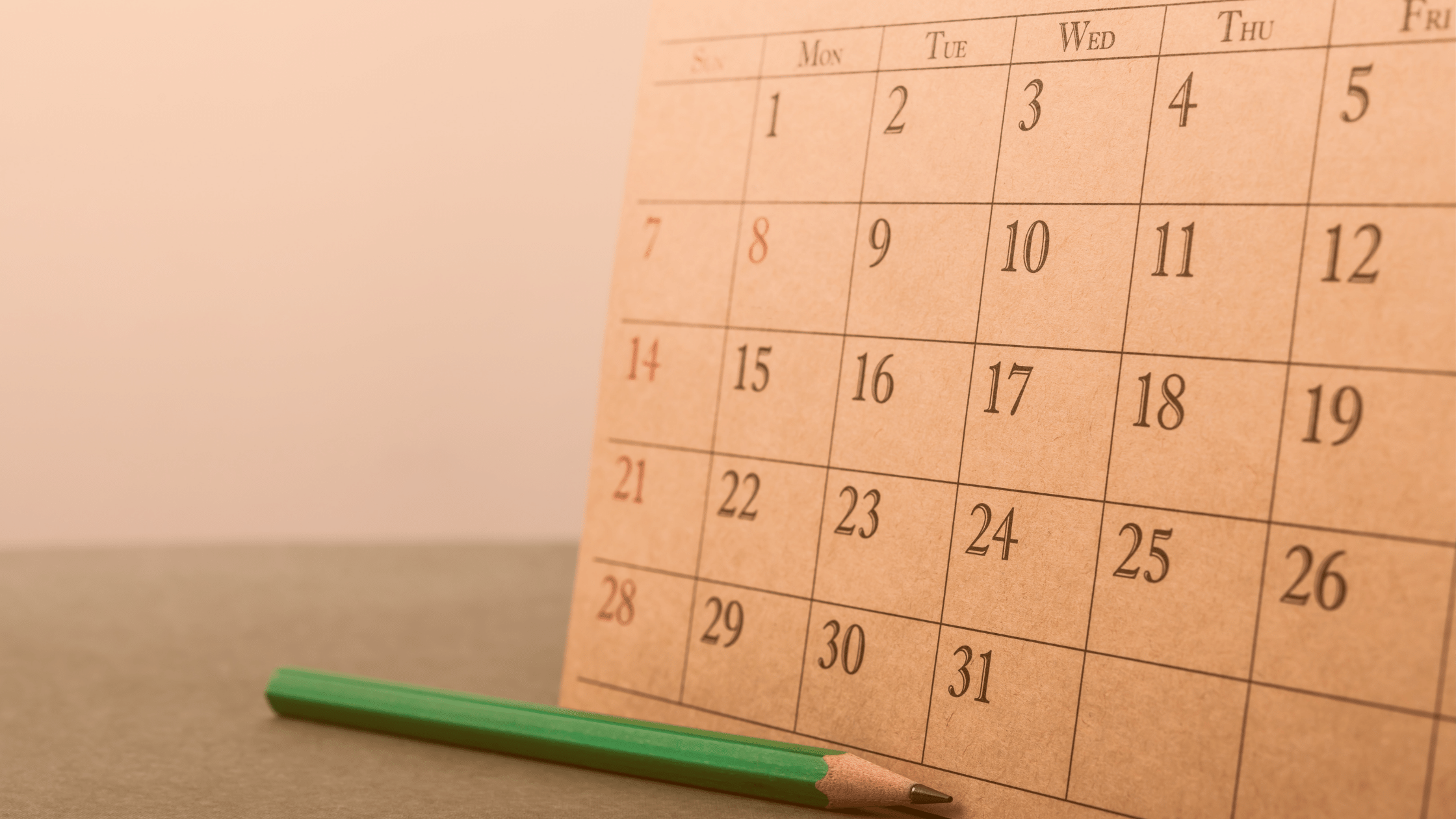 Na biurku stoi kalendarz i leży ołówek.