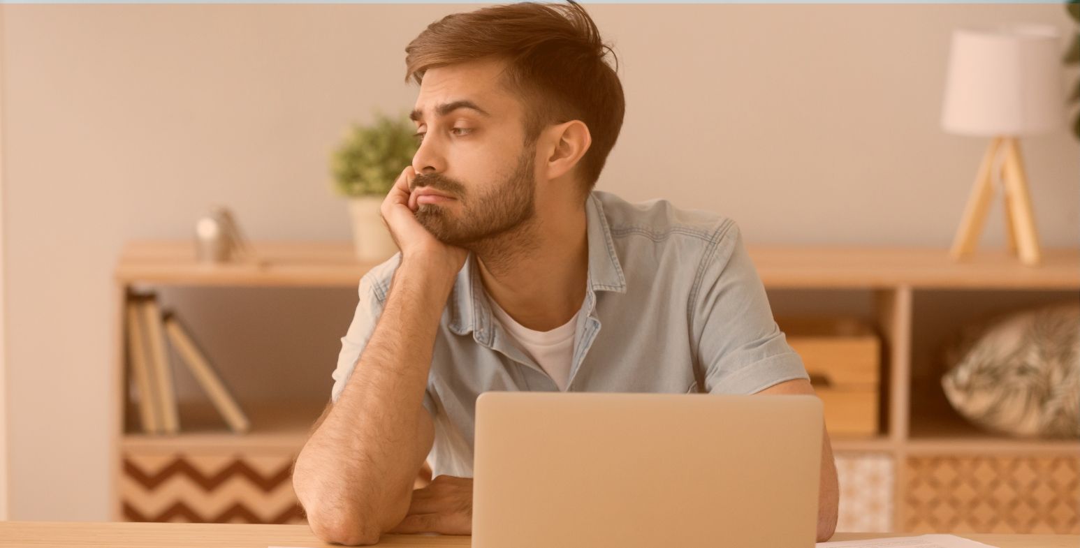 Nieodpowiednio zmotywowany pracownik siedzi przed laptopem i zastanawia się nad utratą pracy